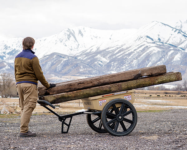 The Warrior cart is loaded with four railroad ties on farm with mountains in the background.