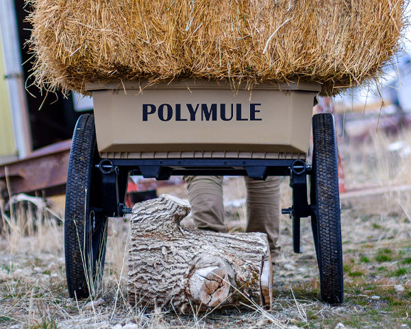 Warrior cart full of hay bales shown from behind. Under the cart is a large stump.