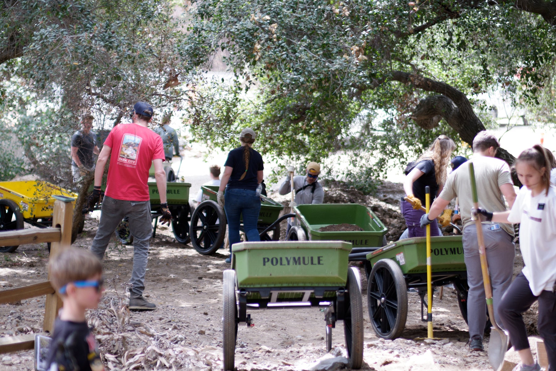 People working with Polymule carts to clear a dirt-filled creek bed