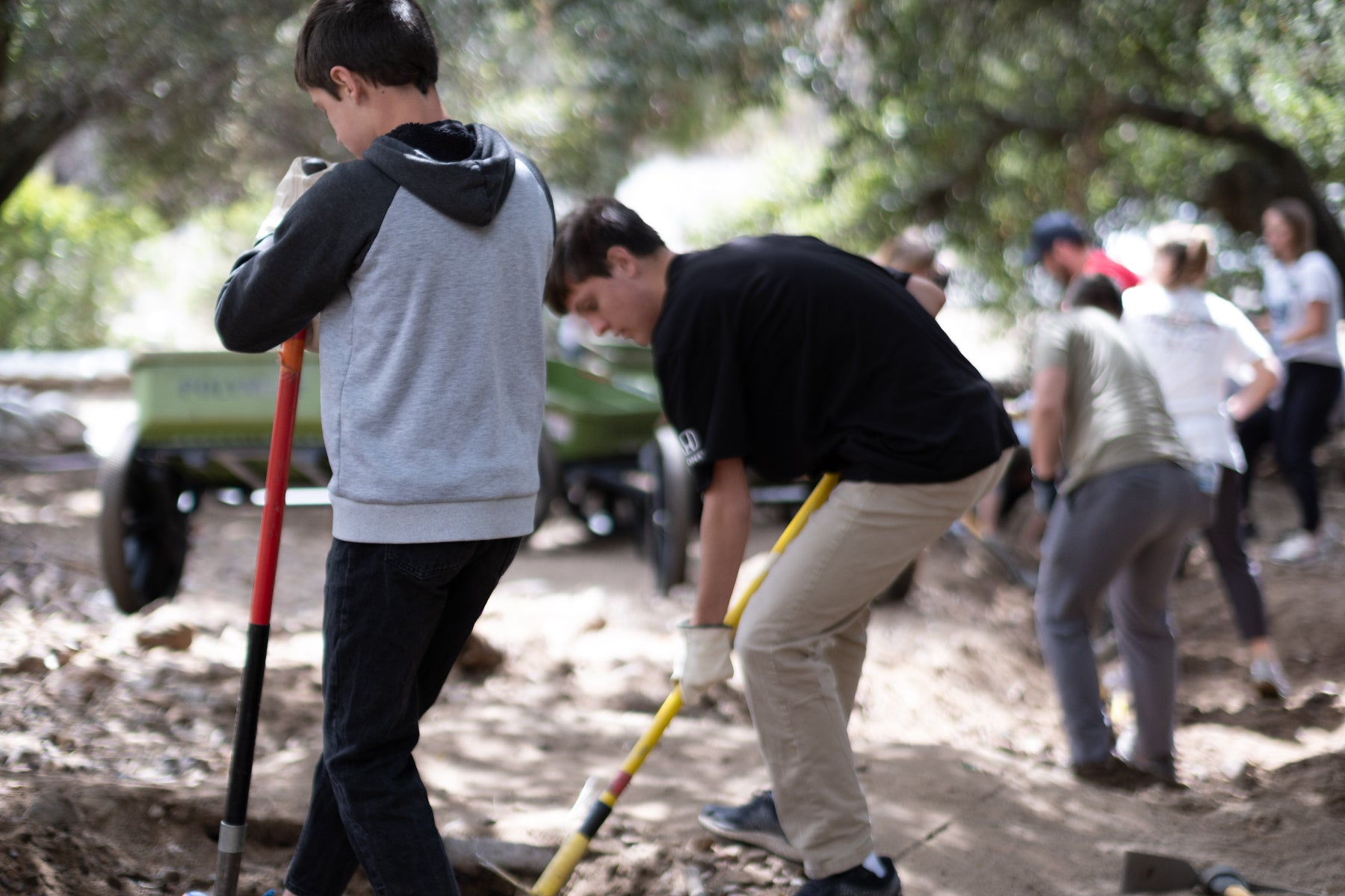 Volunteers use shovels to clear mud and dirt from a creek bed