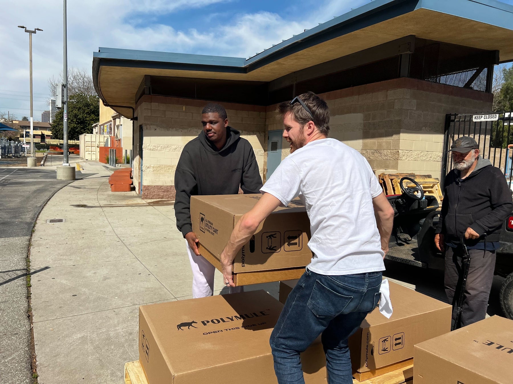 Two men unload a Polymule cart box.