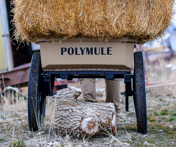 Warrior cart full of hay bales shown from behind. Under the cart is a large stump.